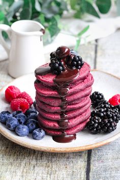 a stack of red velvet pancakes with chocolate sauce and berries