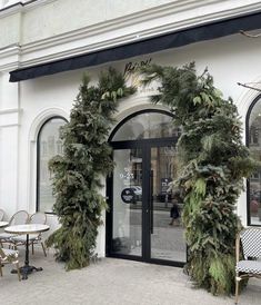 a store front decorated with christmas greenery and wreaths on the outside door,