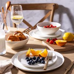 the table is set with fruit, bread and milk