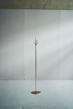 a tall metal planter sitting on top of a white floor next to a brick wall