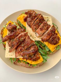 a sandwich with meat, cheese and greens on it is displayed on a white plate