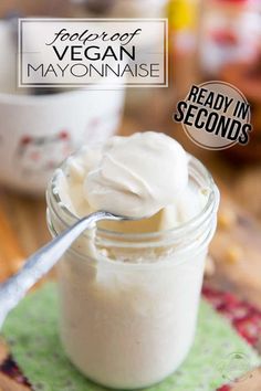 a jar filled with mayonnaise sitting on top of a wooden table next to a spoon