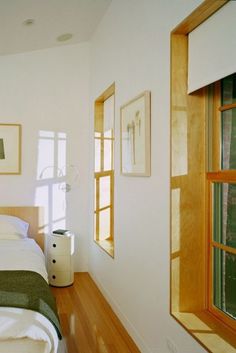 a bed sitting in a bedroom next to two windows