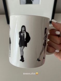 a hand holding a coffee mug with two women on it and one woman wearing a suit