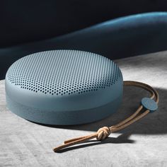 a blue speaker sitting on top of a table next to a rope and pillow with a tag