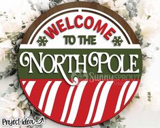 welcome to the north pole sign with white flowers in the background and text on it