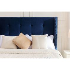 a bed with white pillows and blue headboard