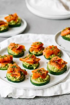 cucumbers with smoked salmon and avocado on them are served on white plates