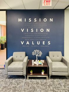 two chairs and a coffee table in front of a blue wall with the words mission vision, value, and exit