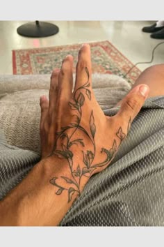 a man's arm with flowers on it and his hand resting on the couch