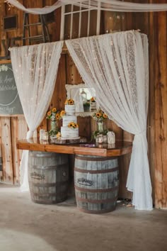 a wedding cake on top of a table next to two barrels with sunflowers