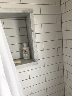 a bathroom with white subway tile and gray grout on the shower wall is shown