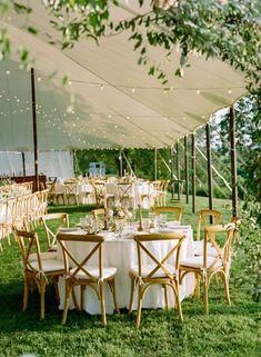 an outdoor tent with tables and chairs set up for a wedding reception under the canopy