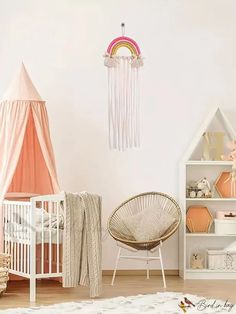 a baby's room with a crib, cot and pink wall hangings