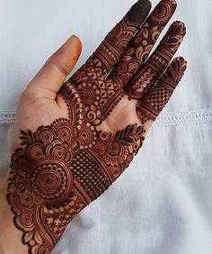 a woman's hand with henna tattoos on it, showing the intricate design