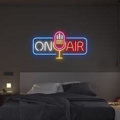 a neon sign that says on air above a bed