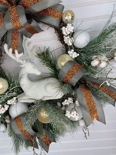 a christmas wreath hanging on the front door with gold and silver ornaments, pine cones, cotton balls and deer's antlers