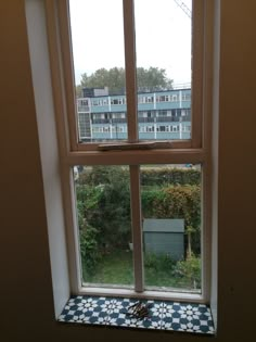 an open window in a room with blue and white checkered flooring on the outside