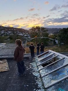 some kids are standing on the roof of a building with broken windows and debris all over it