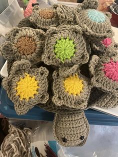 a crocheted turtle with flowers on it's head sitting on a table