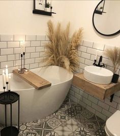 a white bath tub sitting next to a toilet under a bathroom mirror on top of a wooden shelf