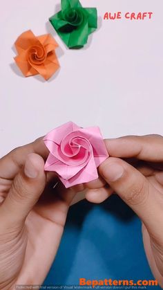 someone is holding an origami rose in their hand with the other paper flowers