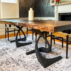 a wooden table with two chairs and a vase on it in front of a fireplace