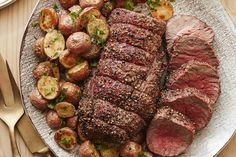 steak, potatoes and vegetables on a plate with utensils next to the plate