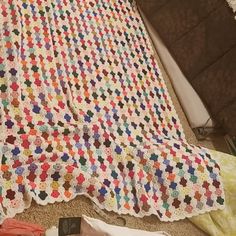 a crocheted blanket is laying on the floor next to some clothes and other items