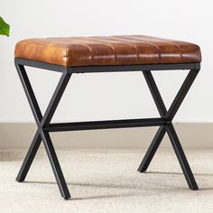 a brown leather bench sitting on top of a carpeted floor next to a plant