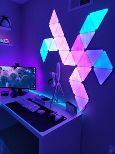 a desk with a computer, keyboard and mouse on it in front of a purple wall