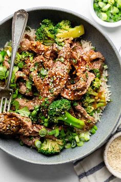 a bowl filled with meat and broccoli on top of rice next to a fork