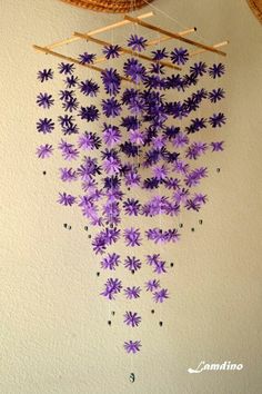 purple flowers are hanging from the ceiling in front of a wall mounted wind chime