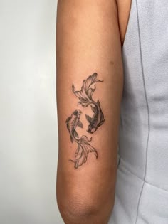 a woman's arm with a fish tattoo on the left side of her arm