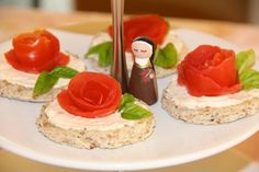 small appetizers with tomatoes and cream cheese on a white plate next to a wooden stick