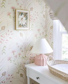 a baby's room with floral wallpaper and a basket on the side table