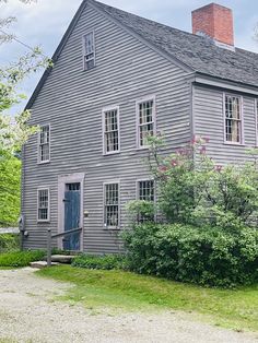 an old gray house sitting on the side of a road