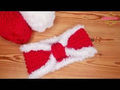 two red and white knitted hats sitting on top of a wooden floor next to a ball of yarn