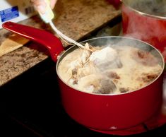 a person stirring food in a pot on the stove with a ladle next to it