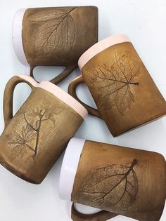 four coffee mugs with leaf designs on them