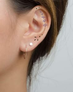 a woman's ear with small tattoos on it