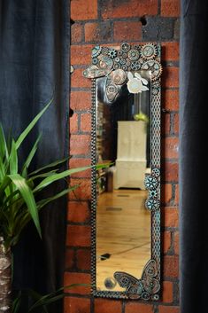 a mirror hanging on the side of a brick wall next to a potted plant