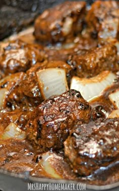 some meat and onions are cooking in a skillet with sauce on the side,