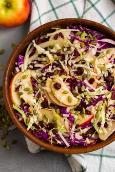 a bowl filled with coleslaw and apples on top of a white table cloth