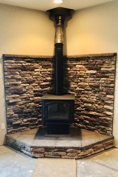 a stone fireplace with a wood burning stove in the center and tile flooring around it