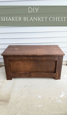 a wooden box sitting on top of a cement floor next to a white building with a blue door