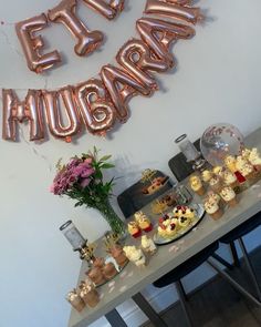 a table topped with lots of desserts and balloons that spell out the word happy birthday