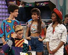 the young people are standing together in front of a tv set with one man wearing a colorful shirt