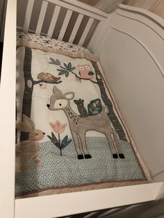 a baby crib with an animal themed blanket on it's bottom and sides