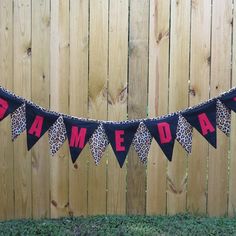 a banner that says game day hanging on a wooden fence in front of a wood fence